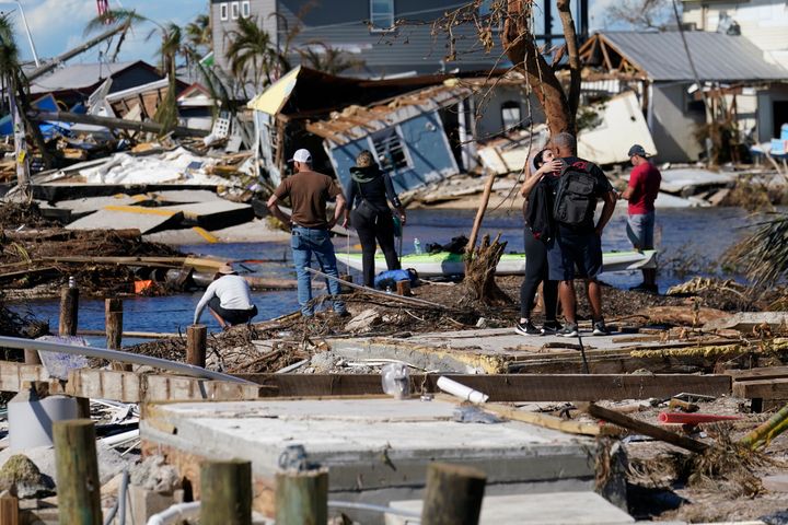 People stand on the destroyed bridge to Pine Island as they view the damage in the aftermath of Hurricane Ian in Matlacha, Fla., on Oct. 2, 2022. The only bridge to the island is heavily damaged so it can only be reached by boat or air.