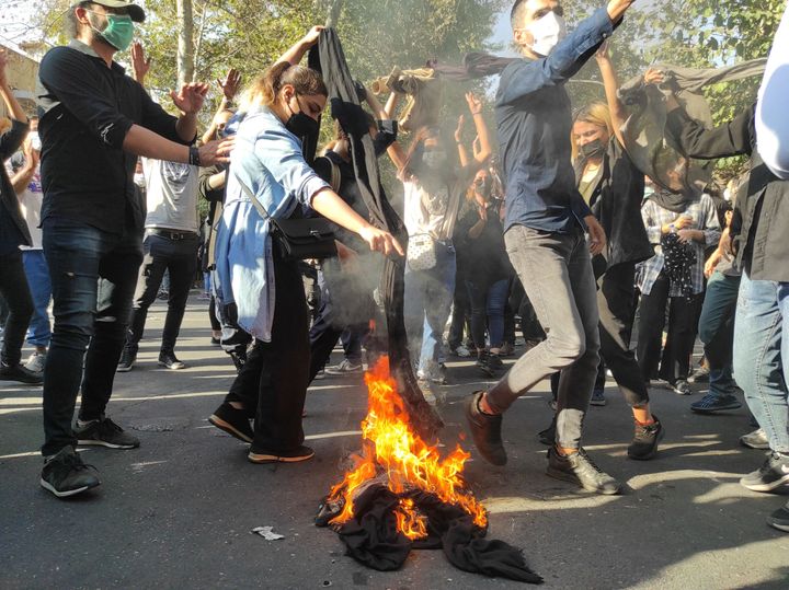 Des manifestants iraniens ont mis le feu à leurs foulards en marchant dans une rue le 1er octobre 2022 à Téhéran, en Iran.  Les protestations contre la mort de Mahsa Amini, une Iranienne de 22 ans, ont continué de s'intensifier malgré la répression des autorités. L'Iranienne de 22 ans est tombée dans le coma et est décédée après avoir été arrêtée à Téhéran par la police des mœurs, pour avoir prétendument violé la pays hijab règles.