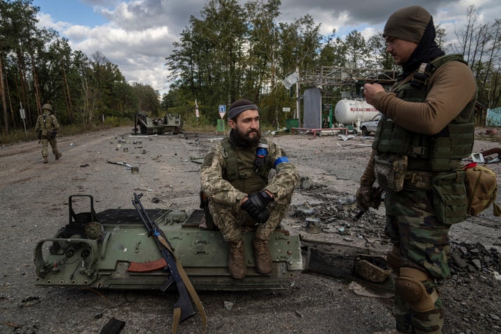 Ukrainian servicemen smoke a cigarettes after they find and identify a dead body of a comrade in the recently recaptured town of Lyman, Ukraine, on Oct. 3, 2022.