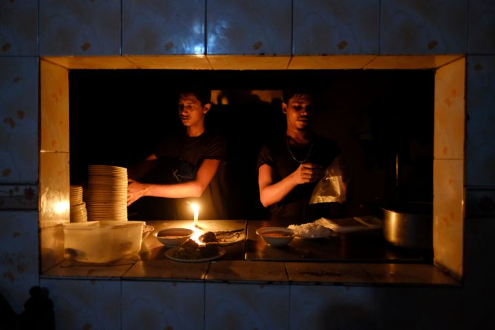 Εργαζόμενοι σε εστιατόρια συσκευάζουν τρόφιμα κάτω από τα φώτα των κεριών κατά τη διάρκεια διακοπής ρεύματος στη Ντάκα του Μπαγκλαντές. Τρίτη, 4 Οκτωβρίου 2022.