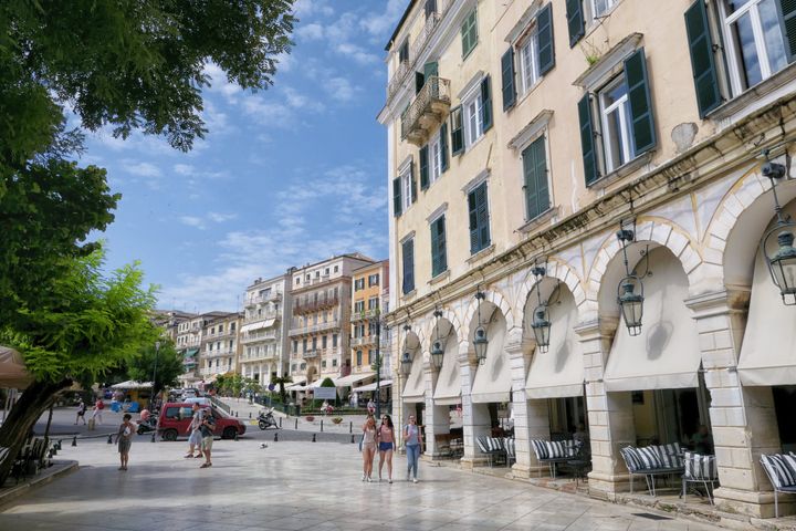 Corfu Town, Greece - May 31, 2018: People walking along pedestrian street at the Corfu town. Historical Liston building with restaurants.