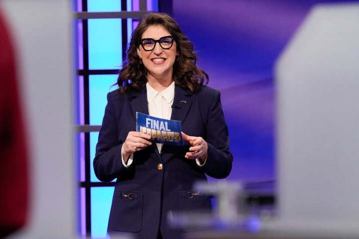 Host Mayim Bialik holds a "Final Jeopardy!" card during the 2022 "Jeopardy! National College Championship."