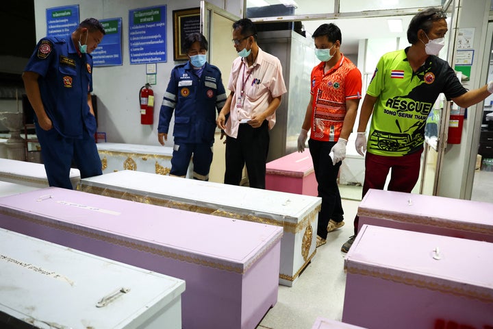 Rescue workers stand next to coffins containing the bodies of the mass shooting victims.