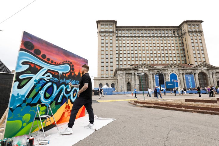 An artist spray paints a canvas at the historic, 105-year old Michigan Central train station prior to a Ford Motor Company press conference to formally announce their plans to renovate the building and turn it and Detroit's Corktown neighborhood into a hub for Ford's auto technology on June 19, 2018 in Detroit, Michigan.