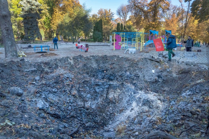 Un homme passe devant un cratère de roquette dans une aire de jeux du parc de la ville du centre de Kyiv, en Ukraine, le 11 octobre 2022.