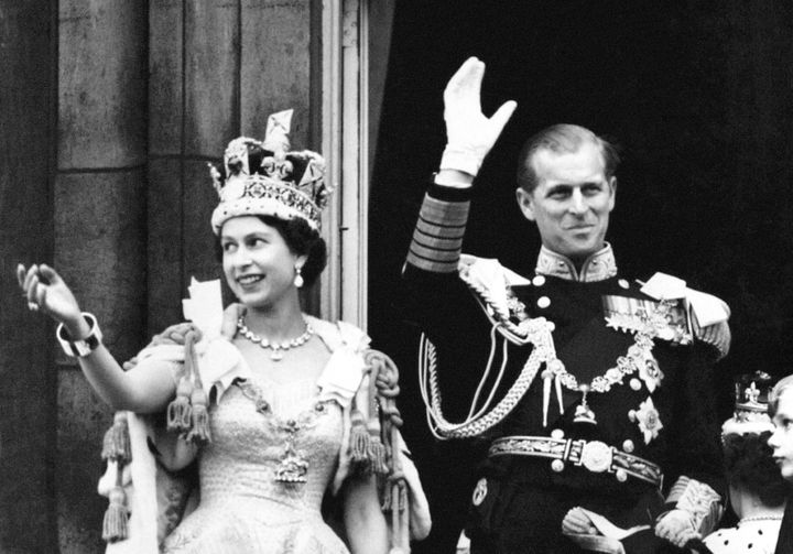 The Queen Elizabeth II, wearing the Imperial State Crown, and the Duke of Edinburgh, dressed in uniform of Admiral of the Fleet, as they wave from the balcony of Buckingham Palace in 1953.