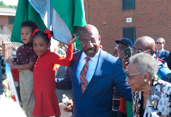 Sen. Raphael Warnock (D-Ga.), center, is up for reelection in November in a pivotal race against Republican and former football star Herschel Walker.