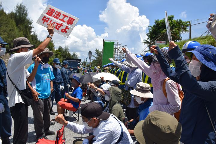 米軍普天間飛行場（宜野湾市）の名護市辺野古移設で、埋め立て用の土砂が搬入される米軍キャンプ・シュワブのゲート前に座り込んで抗議する人たち＝2022年08月25日、沖縄県名護市
