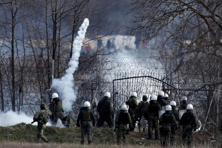 Η ελληνική αστυνομία φρουρεί καθώς μετανάστες συγκεντρώνονται σε φράχτη στα σύνορα στην τουρκική πλευρά, κατά τη διάρκεια συγκρούσεων στα ελληνοτουρκικά σύνορα στις Καστανιές της περιοχής Έβρου, το Σάββατο 7 Μαρτίου 2020. Χιλιάδες πρόσφυγες και άλλοι μετανάστες προσπαθούσαν να εισέλθουν στην Ε.Ε. μέσω της Ελλάδας, αφότου η Τουρκία δήλωσε ότι τα προηγουμένως φυλασσόμενα σύνορά της με την Ευρώπη ήταν ανοιχτά. (AP Photo/Giannis Papanikos)
