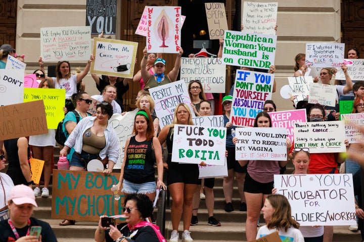 Abortion rights protesters hold placards on the south steps of the Indiana State house during a demonstration.