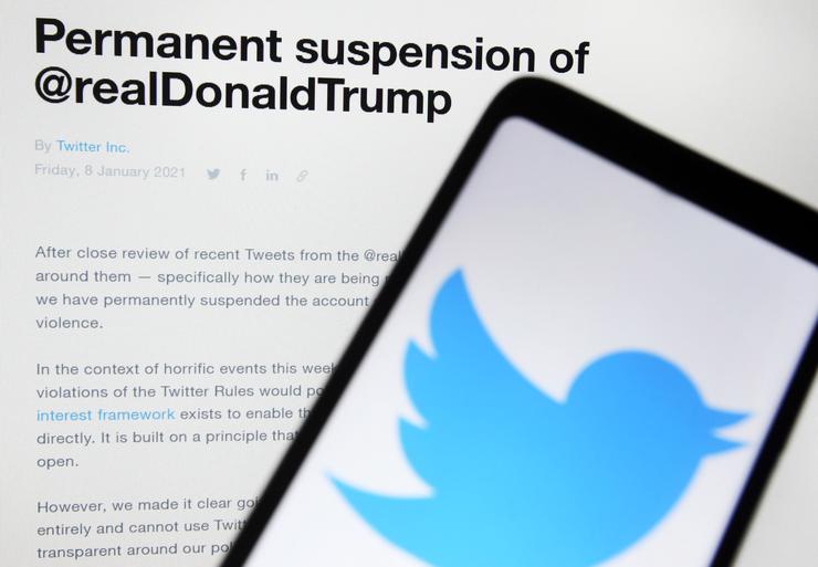 A photo illustration shows a "Permanent suspension of @realDonaldTrump" message from Twitter in front of a mobile phone with the platform's logo.