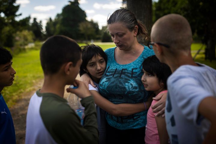 Olga Lopatkina embraces her adopted children in a park in Loue, western France, on July 2, 2022. After two months of negotiation and an initial objection from a senior Russian official, DPR authorities finally agreed to allow a volunteer with power of attorney from Lopatkina to collect her children who were evacuated from Mariupol. 