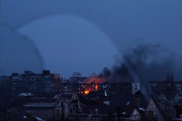 Seen through a broken window, a fire burns at an apartment building after the shelling of a residential district in Mariupol, Ukraine, on March 11, 2022. 