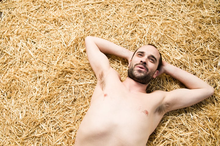 Satisfied guy lies shirtless on straw bed, probably after some satisfactory sex action.