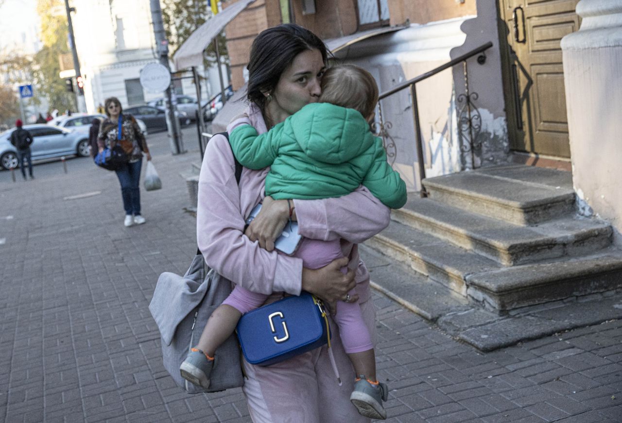 A Ukrainian woman is seen with her child on the sidewalk after the Russian attacks in Kyiv, Ukraine on October 17, 2022.