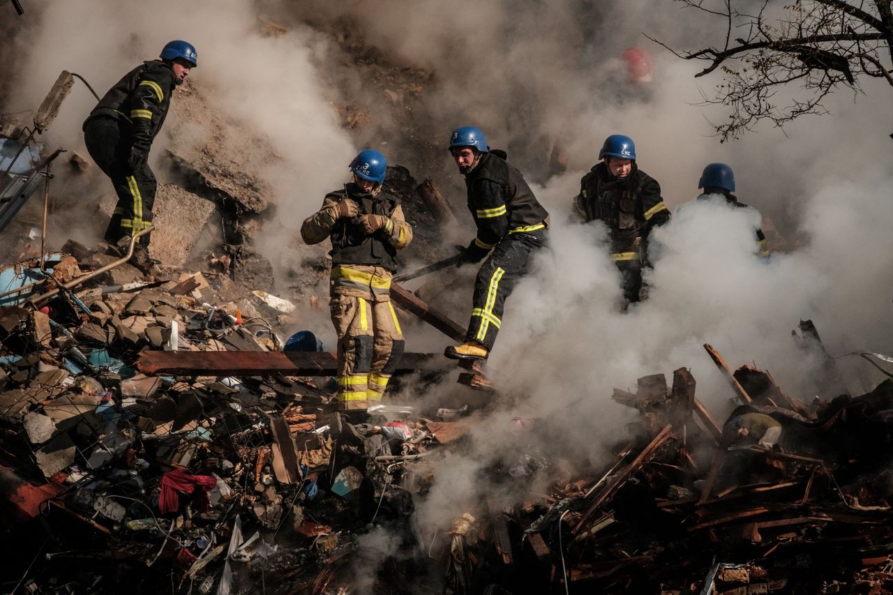 Ukrainian firefighters works on a destroyed building after a drone attack in Kyiv on October 17, 2022.