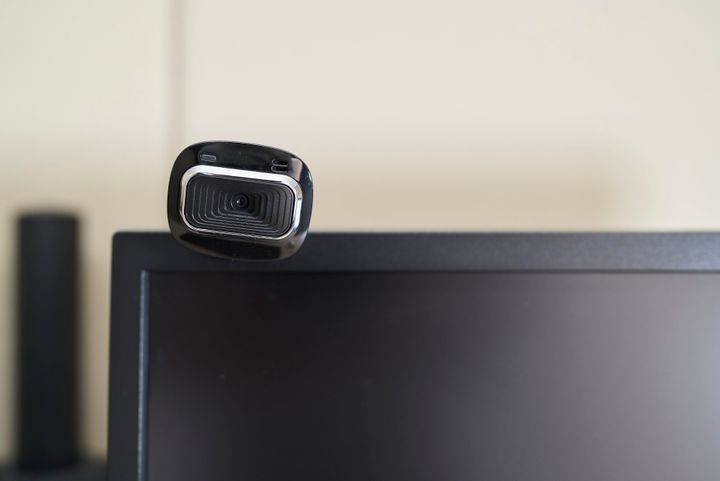 Close up of lens optical web camera on top computer monitor home interior