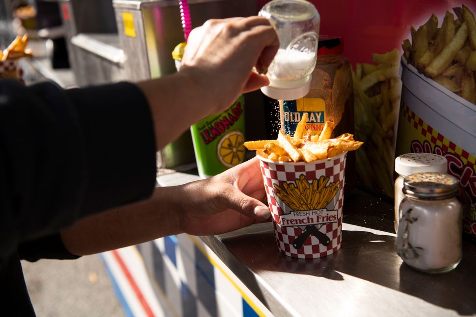A festivalgoer puts salt on their fries.