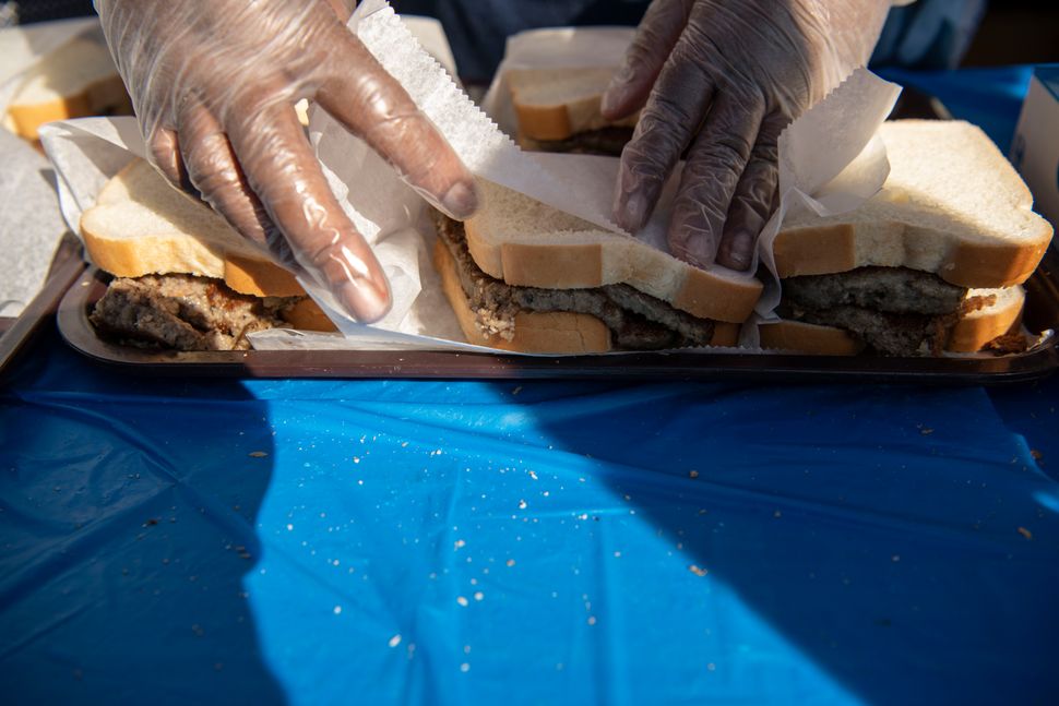 A vendor wraps scrapple sandwiches.