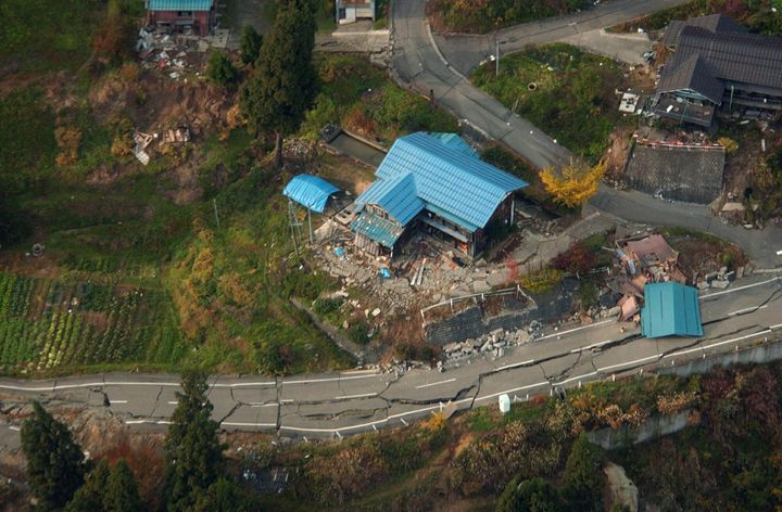 地震でひび割れた道路と壊れた家屋＝2004年11月1日、新潟県山古志村