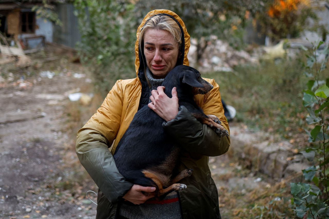 Γυναίκα δακρυσμένη κρατά σφιχτά στην αγκαλιά το σκυλάκι της πλάι στα συντρίμμια της πολυκατοικίας που κατέρρευσε από την ρωσική αεροπορική επιδρομή (Μικολάιβ, 18 Οκτωβρίου 2022) 