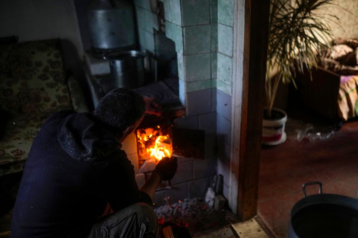 Viktor Palyanitsa lights wood in a stove in his house in Kurylivka, Ukraine, Sunday, Oct. 16, 2022.