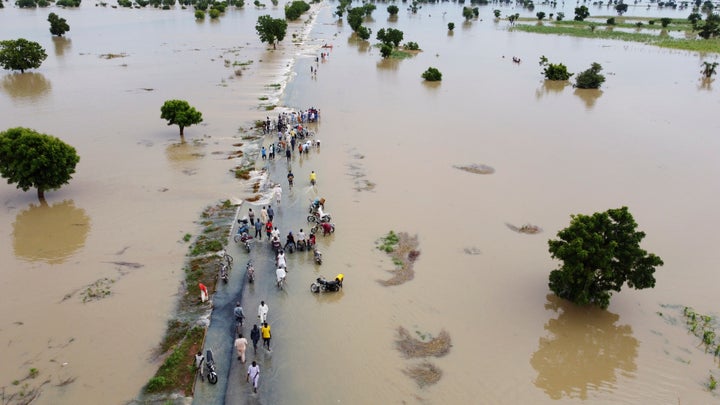 People walk through floodwaters after heavy rainfall in Hadeja, Nigeria, on Sept 19, 2022.