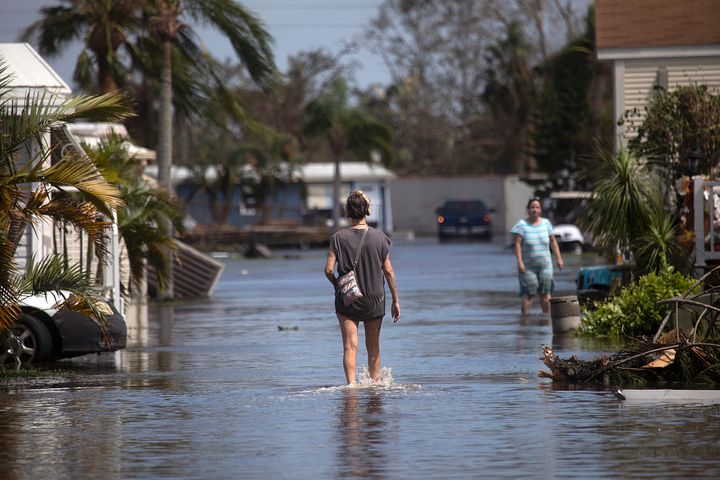 A resident of a mobile home park near Fort Myers Beach walks through floodwaters from Hurricane Ian on Sept. 29. Health officials in Florida are advising people to wear protective boots if entering the water, which can carry high levels of bacteria.