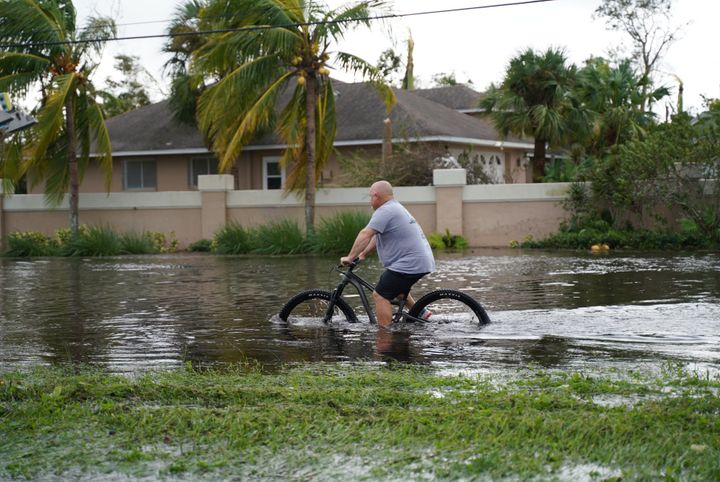 A man tries to ride a bike in a road flooded by Hurricane Ian in Fort Myers. The bacteria grows faster in warmer months and can be amplified by sewage spills, according to health officials.