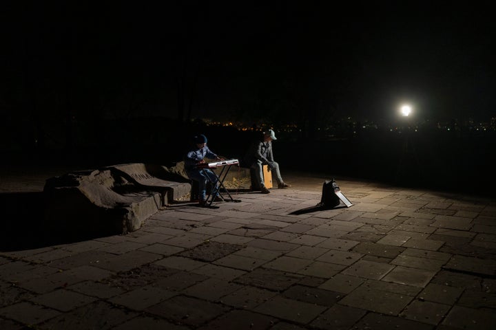 Street musicians play their instruments in a square without electric lights in Kyiv, Ukraine, on Oct. 18, 2022.