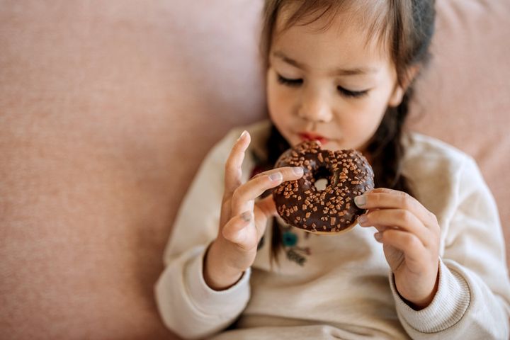 Cute little girl eating chocolate doughnut