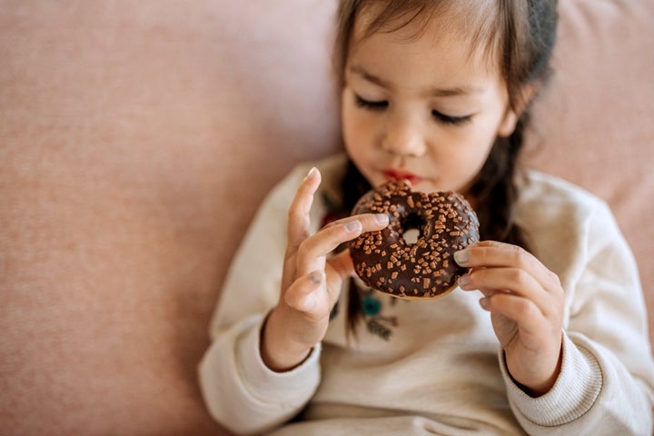 Cute little girl eating chocolate doughnut