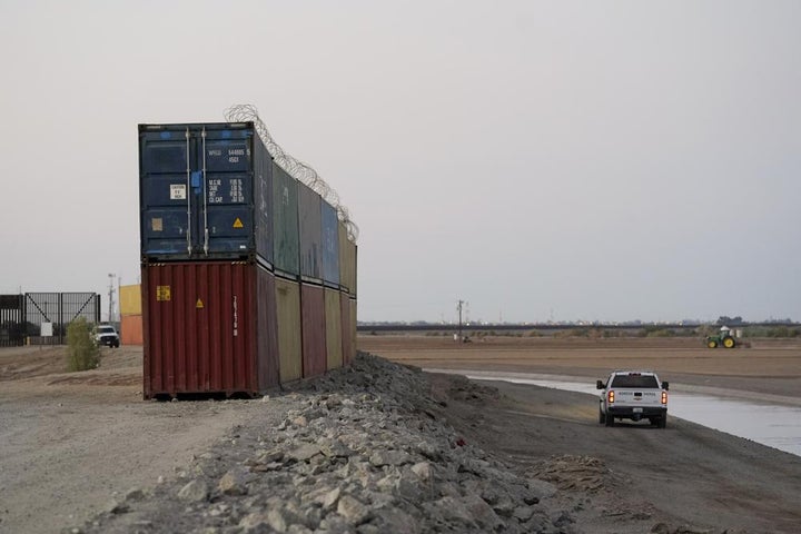 FILE - Border Patrol agents patrol along a line of shipping containers stacked near the border on Aug. 23, 2022, near Yuma, Ariz. The Cocopah Indian Tribe is welcoming the federal government's call for the state of Arizona to remove a series of double-stacked shipping containers placed along the U.S.-Mexico border near the desert city of Yuma, saying they are unauthorized and violate U.S. law.