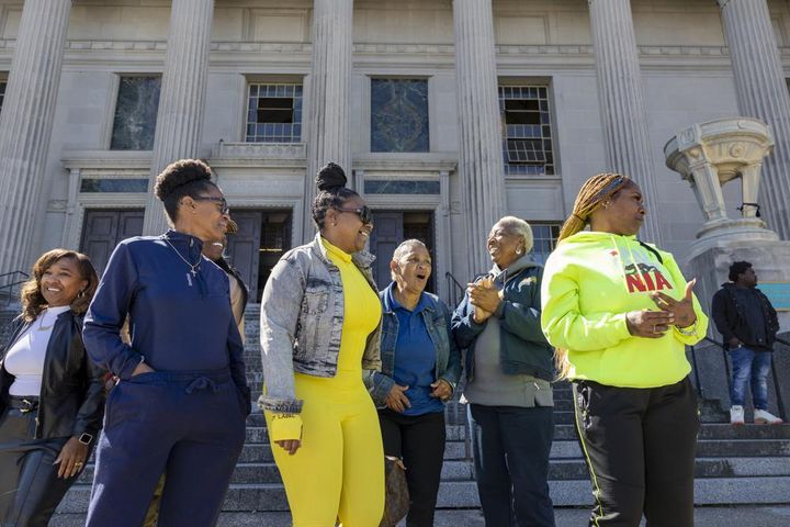 Family members of Leroy Nelson, Bernell Juluke, and Kunta Gable smile as they stand outside Orleans Parish Criminal District Court in New Orleans.