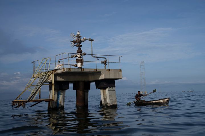 ΑΡΧΕΙΟ - Ένας ψαράς περνά μπροστά από μια ανενεργή γεώτρηση πετρελαίου στη λίμνη Maracaibo στη Βενεζουέλα, στις αρχές του Οκτωβρίου 12, 2022. Ένα κατηγορητήριο 49 σελίδων που αποσφραγίστηκε στις 20 Οκτωβρίου στο ομοσπονδιακό δικαστήριο της Νέας Υόρκης έχει κατηγορήσει επτά άτομα για συνωμοσία για λαθρεμπόριο πετρελαίου από την PDVSA. Aγοράζουν ευαίσθητη στρατιωτική τεχνολογία των ΗΠΑ και ξεπλένουν δεκάδες εκατομμύρια δολάρια για λογαριασμό πλούσιων Ρώσων επιχειρηματιών, αναφέρεται στο κατηγορητήριο. (AP Photo/Ariana Cubillos, File)