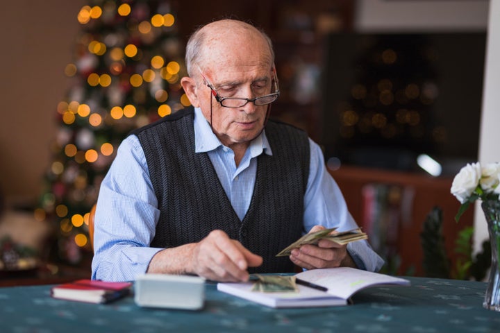 Serious mature man with eyeglasses counting money at home