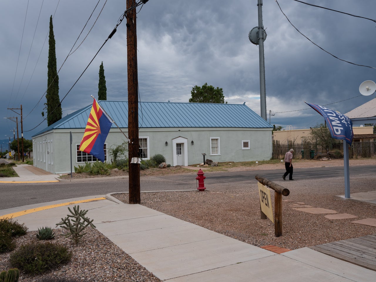 An elderly man walks past a building flying the Arizona flag along with a Trump 2024 flag in Tombstone, Arizona.