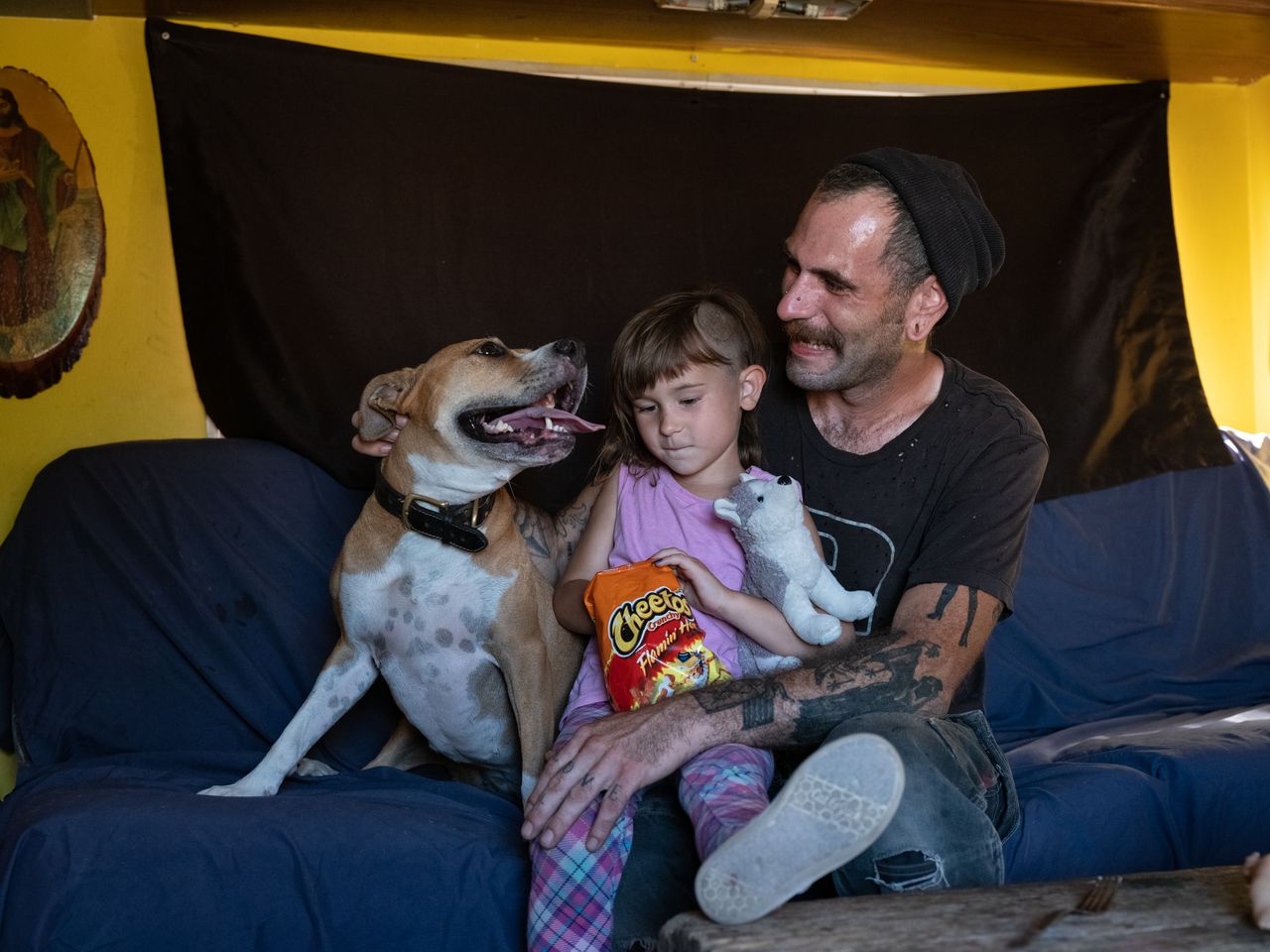 Chris Geddis sits in his RV with his daughter, Lilith, and their dog, Bourbon.