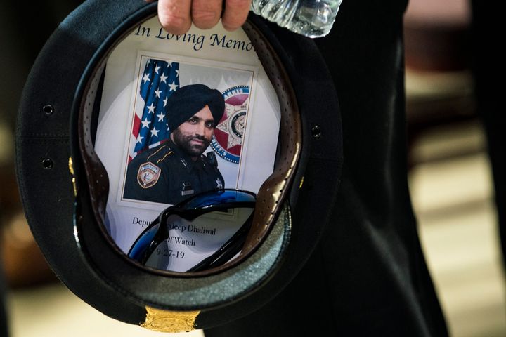 A Houston Police officer places a picture of Harris County Sheriff's Deputy Sandeep Dhaliwal in his hat during the deputy's funeral at Berry Center on Oct. 2, 2019, in Houston.