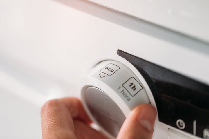 Close up of hand adjusting dishwasher to economy cycle