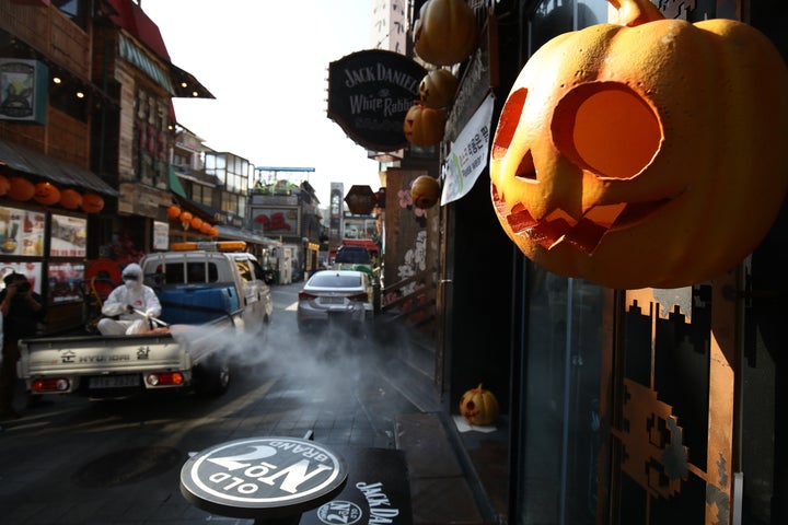 Un responsable de la santé pulvérise une solution antiseptique dans les magasins extérieurs d'une ruelle du quartier Itaewon de Séoul pour empêcher la propagation du coronavirus à Halloween en octobre 2021. 