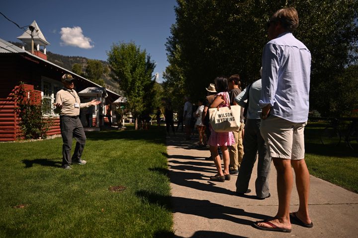 A poll worker speaks to people as they wait in line to vote in the Republican primary election at the Old Wilson Schoolhouse Community Center in Wilson, Wyoming, on Aug. 16, 2022.