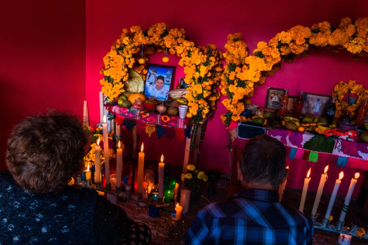 A Mexican couple sits in front of an altar of the dead (Altar de Muertos), a religious site honoring the deceased, during the Day of the Dead (Día de los Muertos) celebrations on Nov. 1, 2021, in Metlatónoc, Mexico. Based on the belief that the souls of the departed may come back to this world on that day, people gather to pray, eat, drink or play music, to remember friends or family members who have died and to support their souls on the spiritual journey.