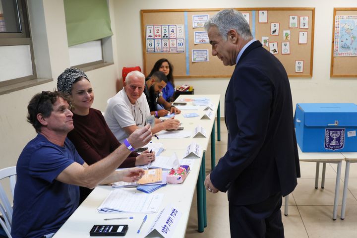 Israeli Prime Minister Yair Lapid, right, arrives to cast his vote in the country's fifth election in four years, at a polling station in Tel Aviv on Nov. 1, 2022. For the fifth time since 2019, Israelis were voting in national elections on Tuesday, hoping to break the political deadlock that has paralyzed the country for the past three and a half years. 