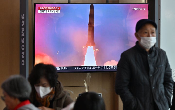 People watch a television screen showing a news broadcast with file footage of a North Korean missile test on November 2, 2022.