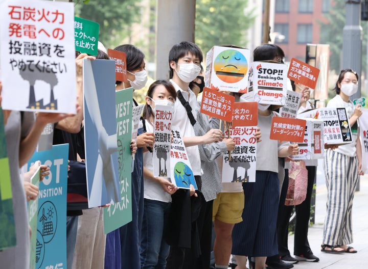 三井住友フィナンシャルグループの株主総会が開かれる本社前で、石炭火力発電への投融資に抗議するプラカードを掲げる人たち（6月、東京都千代田区）