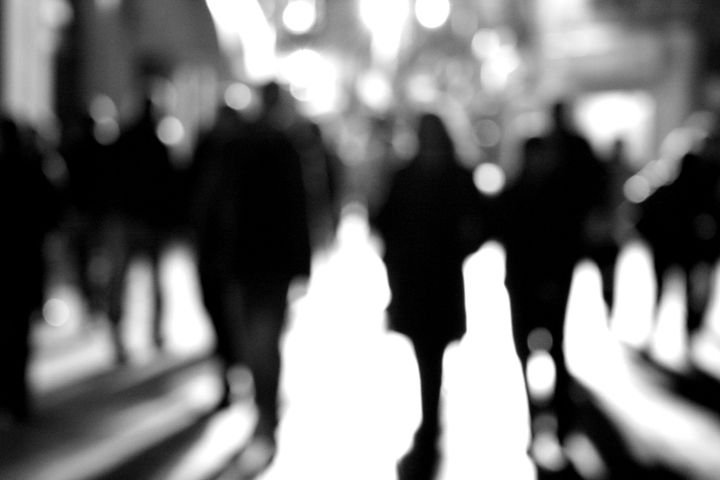 Silhouettes of people walking in the street of a city.