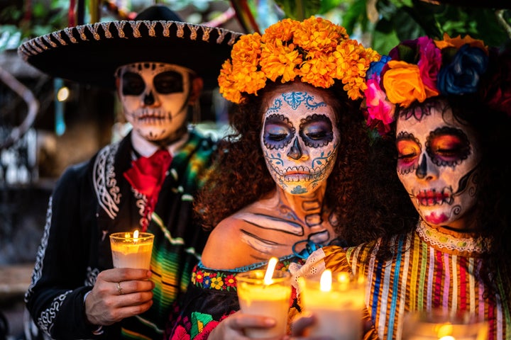 Friends celebrating the day of the dead lighting candle