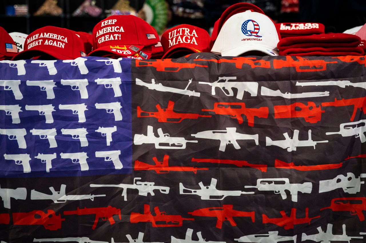 Hand gun- and rifle-themed American flags, hats and other MAGA gear is sold during the ReAwaken America Tour.