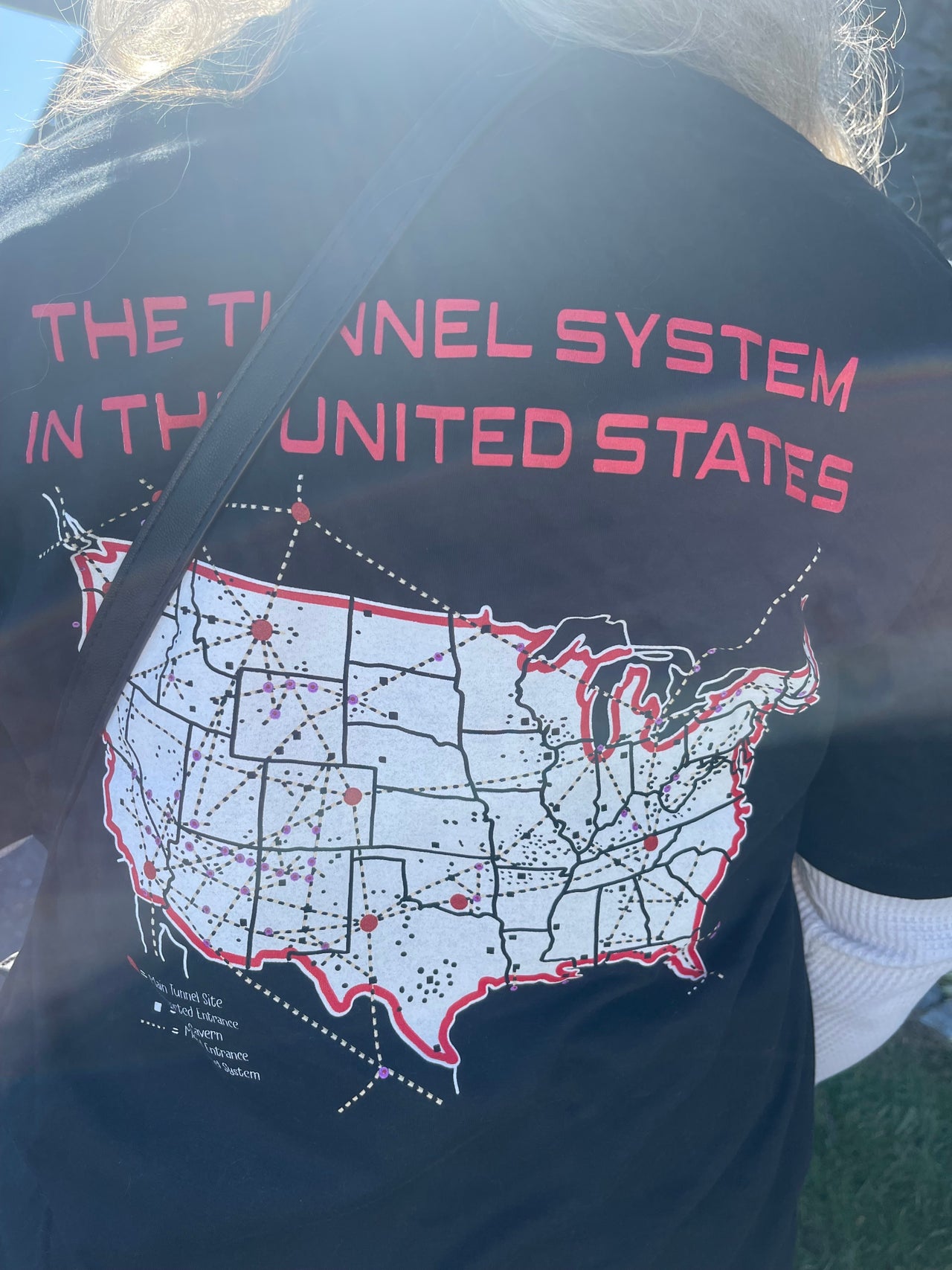 A woman at the Great ReAwakening event shows off a shirt mapping out underground tunnels across the U.S. where she believes the Illuminati are harvesting children's blood.